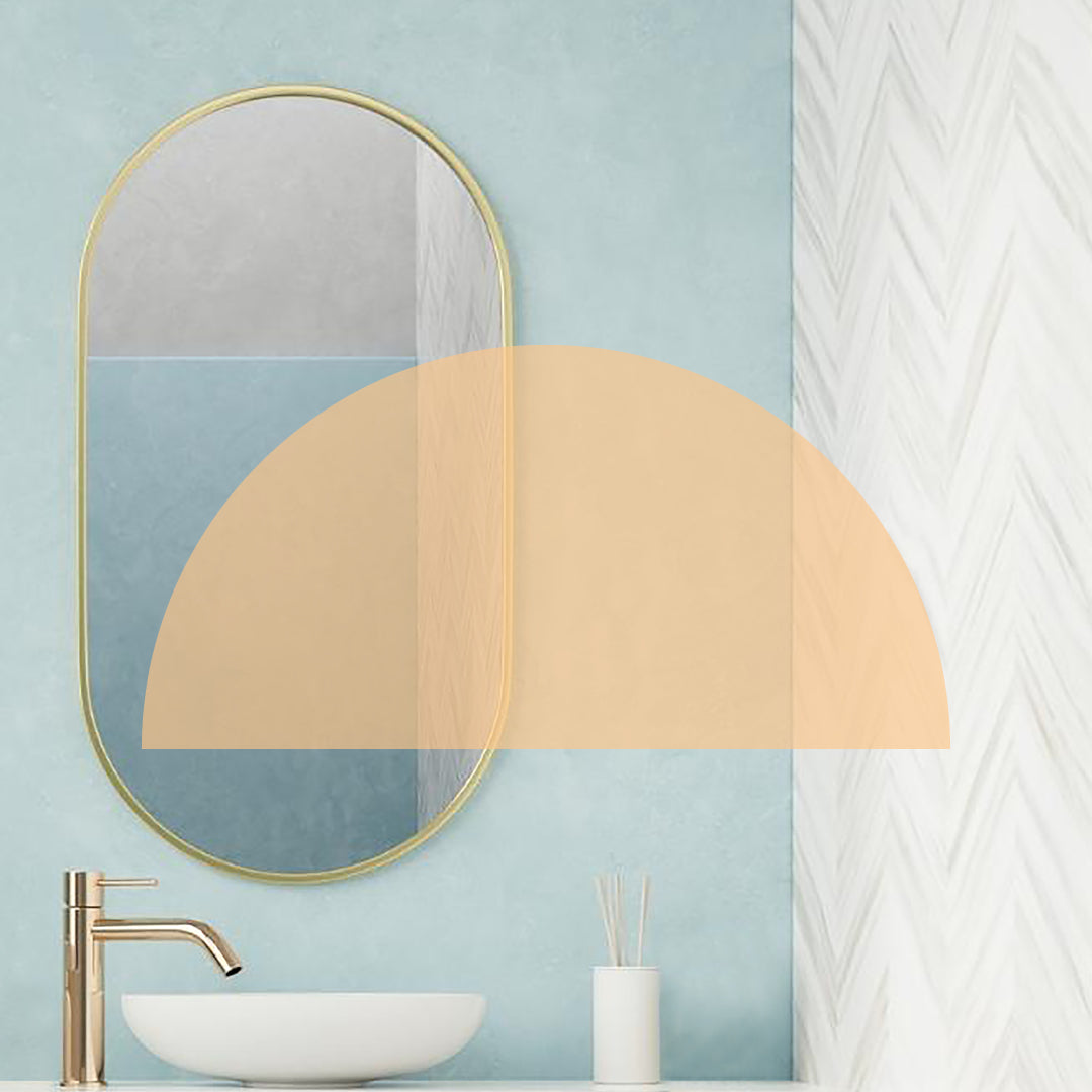 Sleek bathroom with gold oblong mirror, gold tap, white basin and white accessories overlaid with an orange half circle shape.