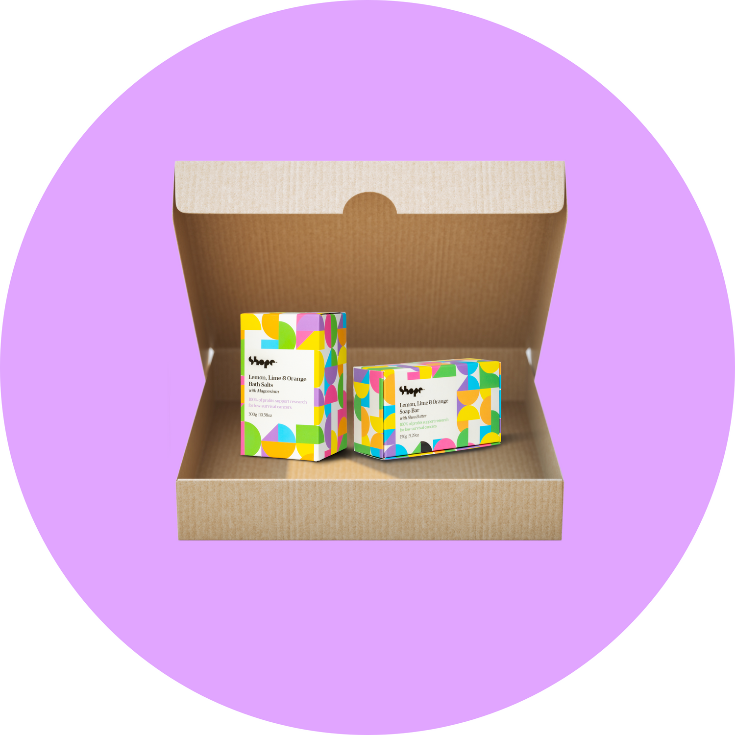 Boxed SHOPE lemon lime and orange bath salts and soap bar, inside brown shipping box with purple circle background.