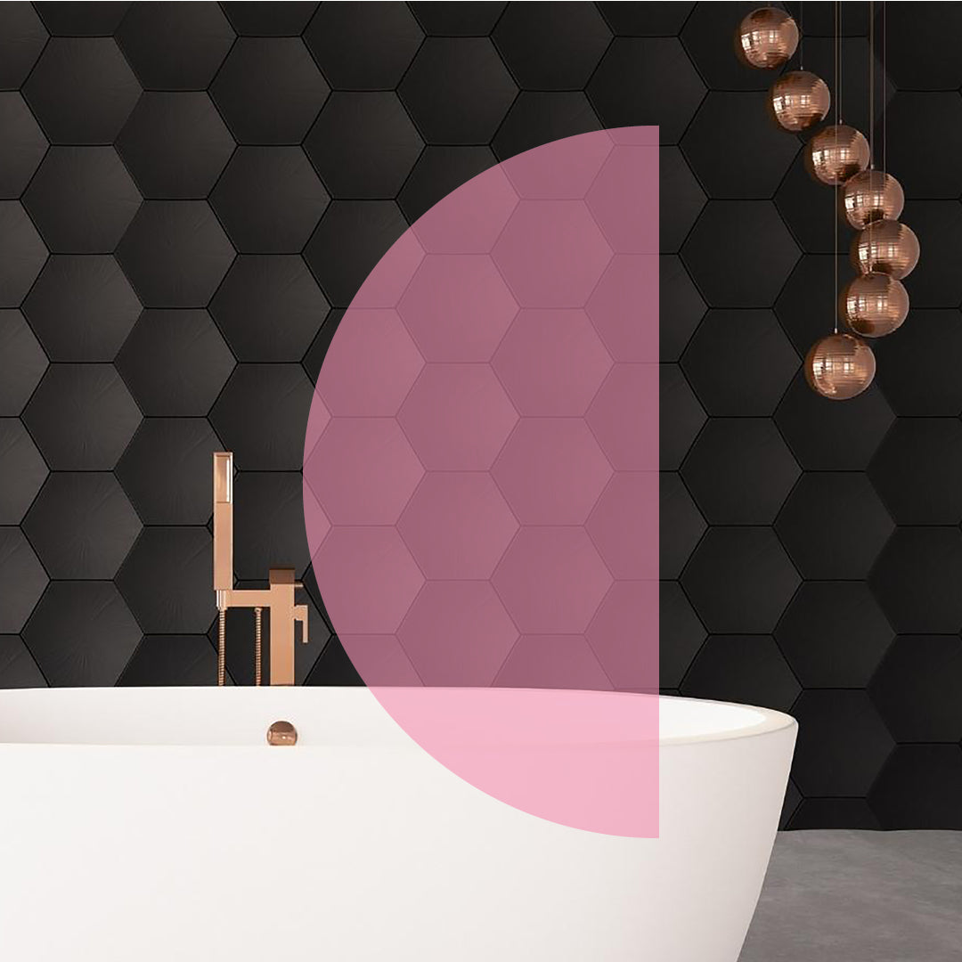 Large black honeybee wall tiles with rose gold tap and accessories against white bath, overlaid with pink half-circle shape.