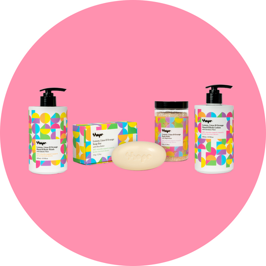 Unboxed SHOPE lemon lime and orange suite of products, with pink circle background. Products include hand and body wash, hand and body lotion, bath salts and soap bar.